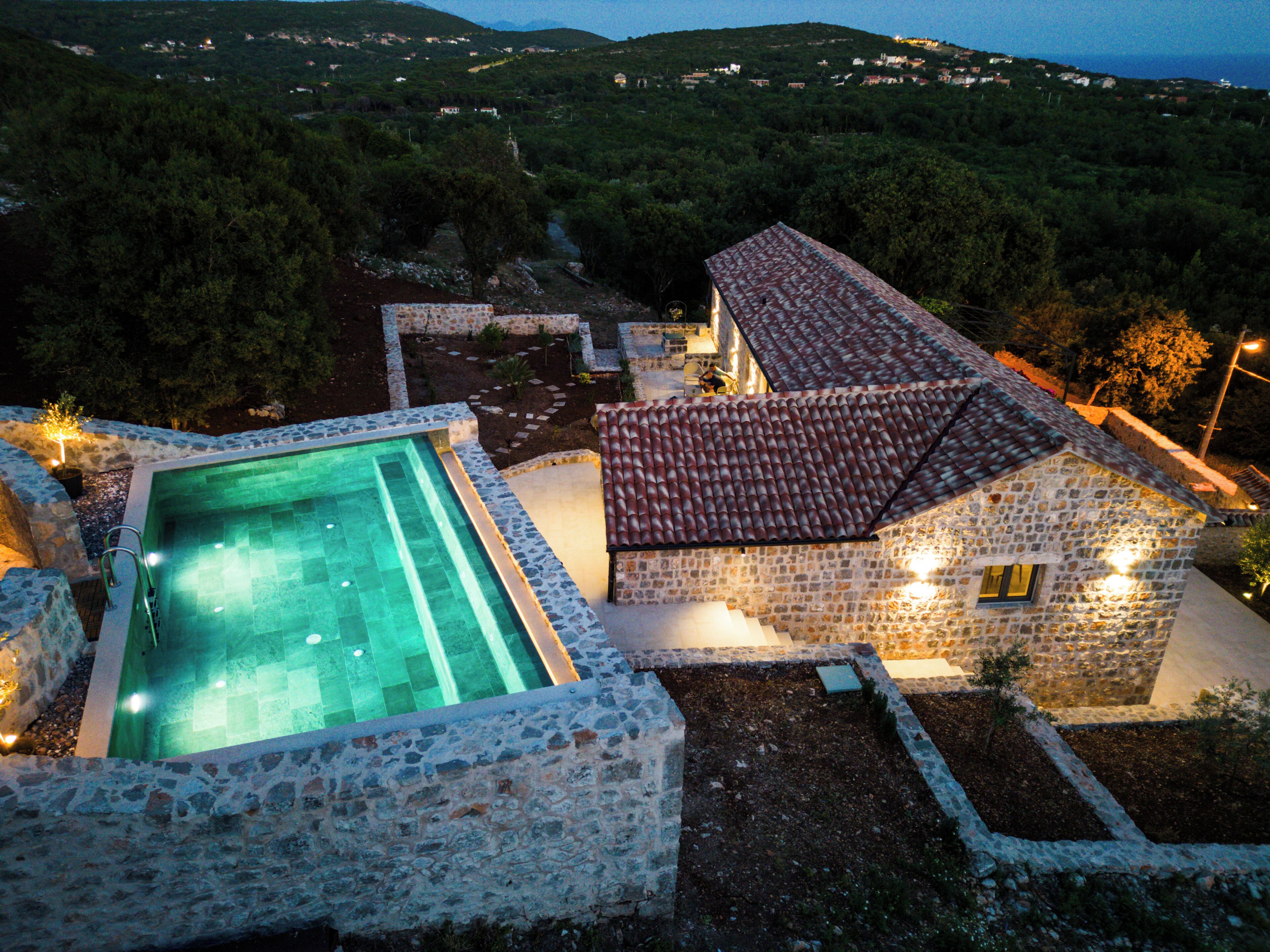 A stone house with a swimming pool and a stone wall.