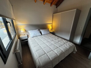 Une chambre à coucher avec un lit, deux lampes de chevet, un radiateur et une fenêtre.