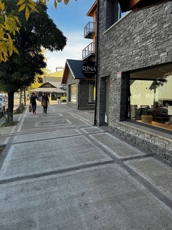 A street with a stone building, a sign reading 'RINA,' and a clear sky.