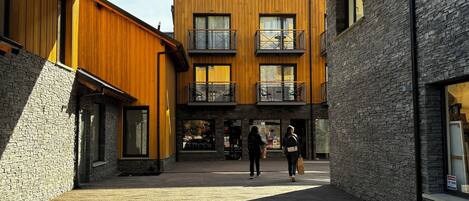 A modern building with a central courtyard, wooden and stone facades, and multiple balconies.
