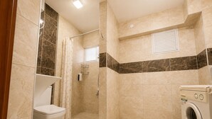 Un bagno con doccia, WC e lavatrice.