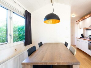 A modern kitchen with white cabinets, a wooden countertop, and a black pendant light. - Holiday Home for 4 People (Noordwijk)