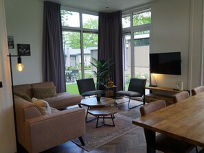 Ein modernes Wohnzimmer mit einer Couch, Sesseln, einem Couchtisch und einem Fernseher.