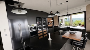 A modern kitchen with built-in appliances, a dining area with a wooden table, and a view of greenery outside. - Lovely 2-bedroom house with AC in Playa Hermosa (Playa Hermosa)