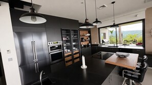 Eine moderne Küche mit integrierten Geräten, ein Essbereich mit Holztisch und Blick ins Grüne.