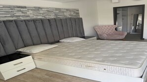 A bedroom with a bed, a chair, a nightstand, and a wall with a textured pattern.