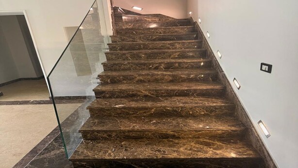 A staircase with glass railings and recessed lighting.