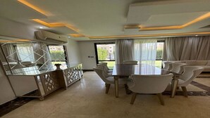 A dining area with a table and chairs, a decorative cabinet, and a large mirror.