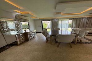 A dining area with a table and chairs, a decorative cabinet, and a large mirror. - Lovely 3-bedroom apartment with AC in El Sheikh Zayed (el sheikh zayed)