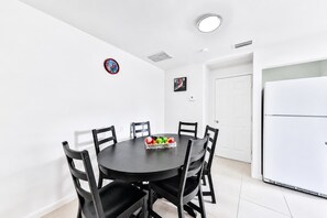 A dining area with a round table, black chairs, and a fruit bowl. - Villa Estudiantil STR-2000. (Hollywood)
