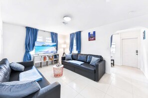 A modern living room with a flat-screen TV, two sofas, a coffee table, and a bookshelf. - Villa Estudiantil STR-2000. (Hollywood)