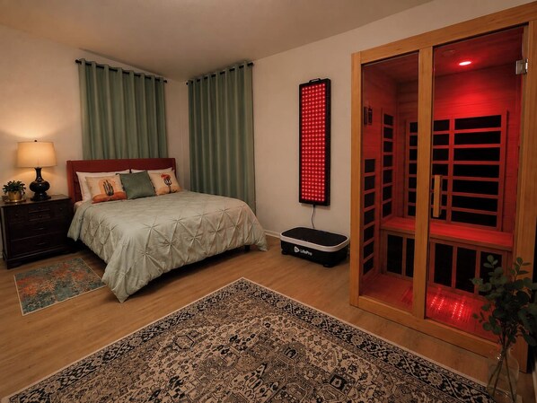 Un dormitorio con una cama, una mesita de noche, un panel de luz roja, un armario de madera y una alfombra estampada.