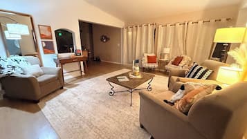 Sala de estar com sofá, poltronas, mesa de centro e abajur.