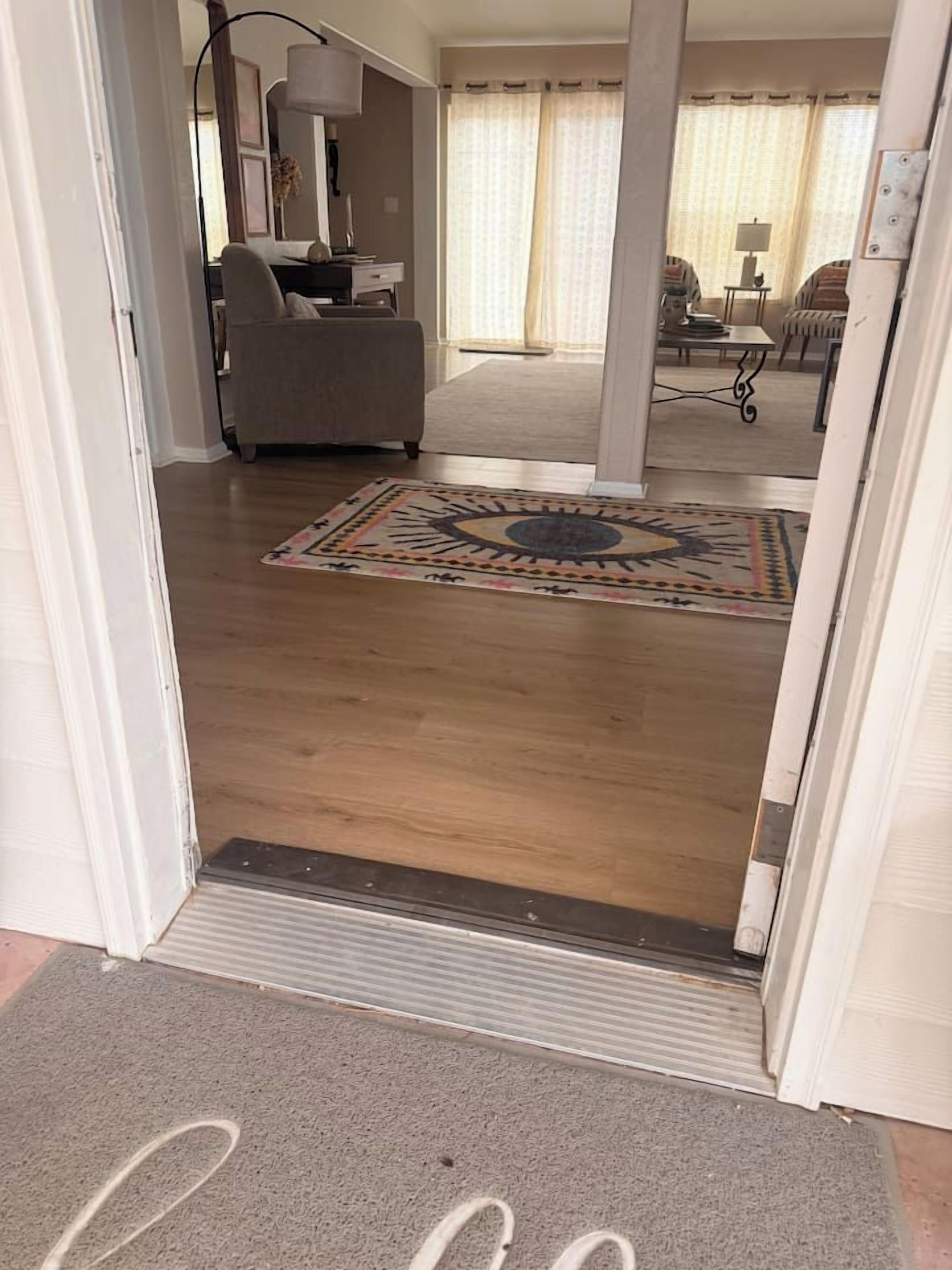 Un pasillo con suelo de madera, un tapete estampado y un felpudo con la palabra 'welcome'.
