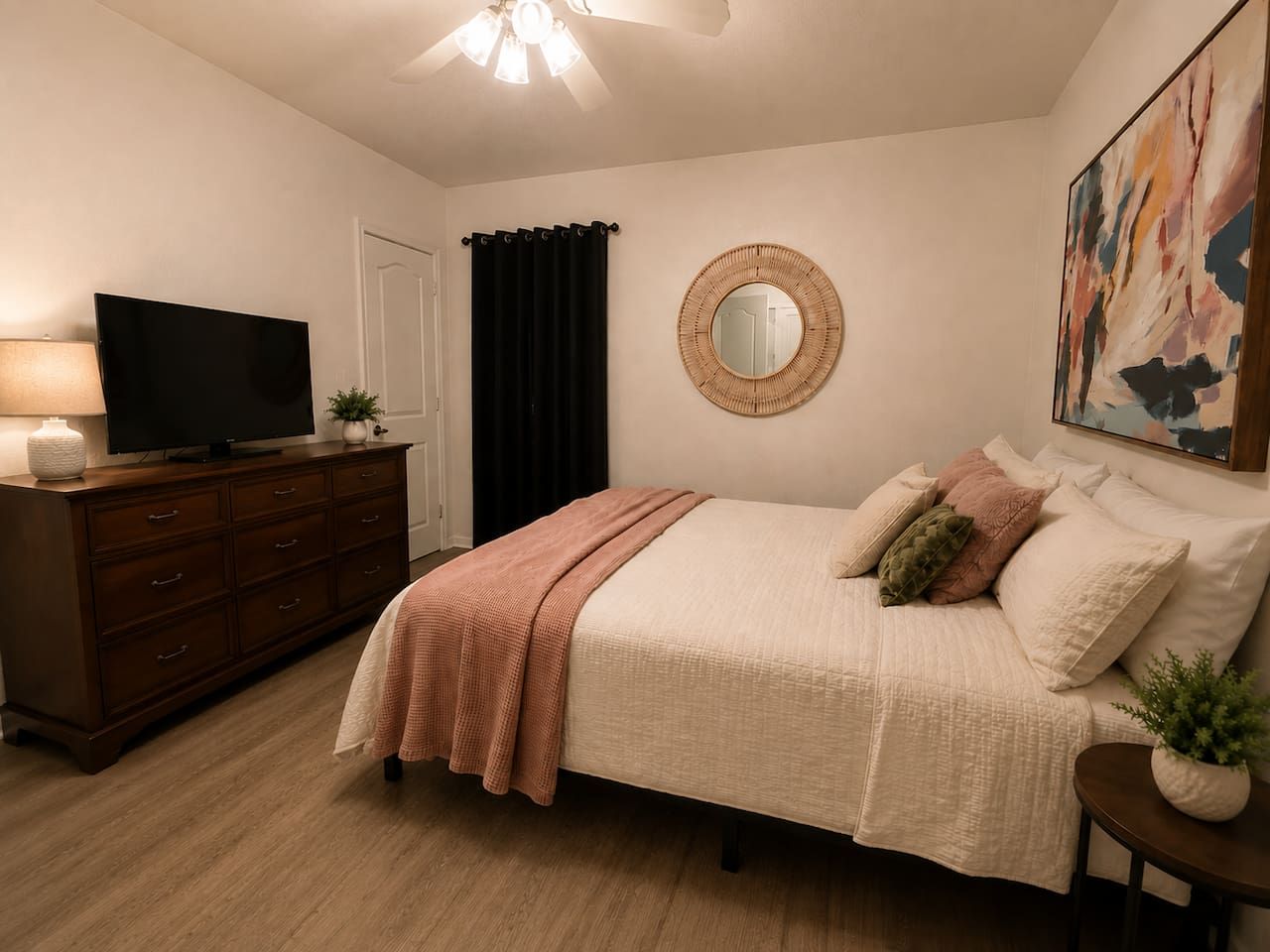 Ein Schlafzimmer mit Bett, Schminktisch, Fernseher und Kunstwerken.
