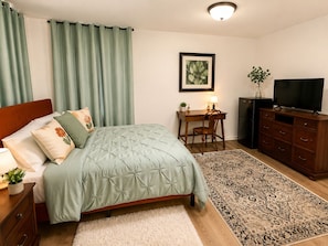 Une chambre à coucher comprenant un lit, un bureau, une chaise, une télévision et une commode.