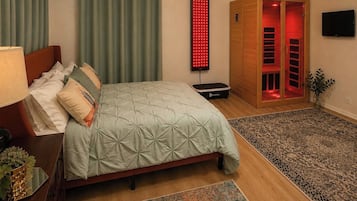 Quarto com cama, cadeira de massagem, painel de luz vermelha, armário de madeira e televisão.