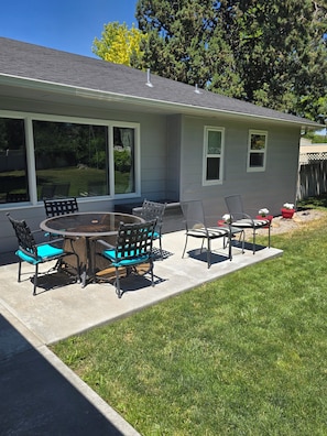 A house with a patio, a round table, and outdoor chairs.