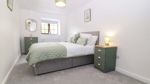 A bedroom with a bed, bedside tables, a window, and a lamp. - Cil Y Coed (Gaerwen)