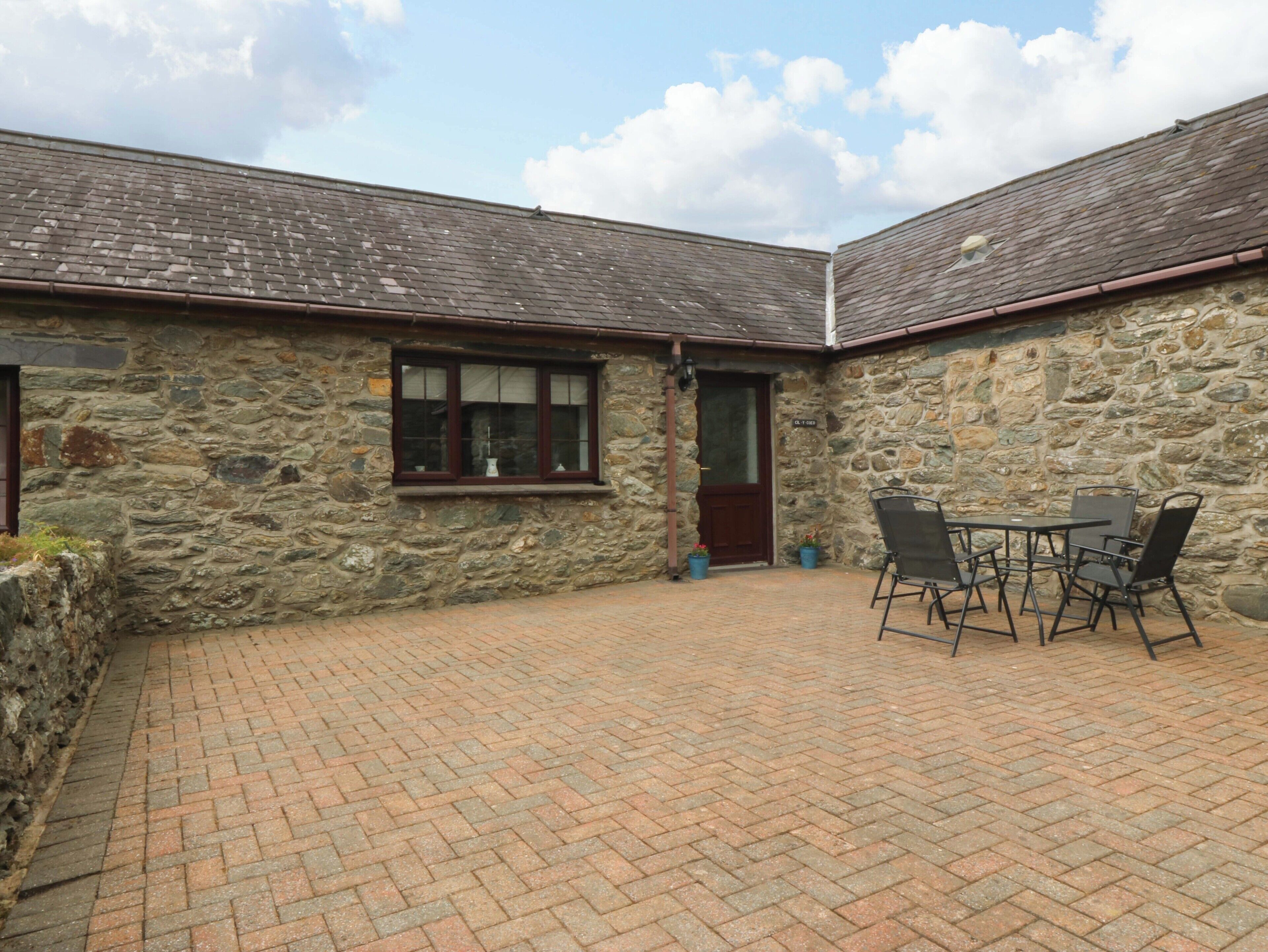 A stone building with a tiled patio, a door, and a window.