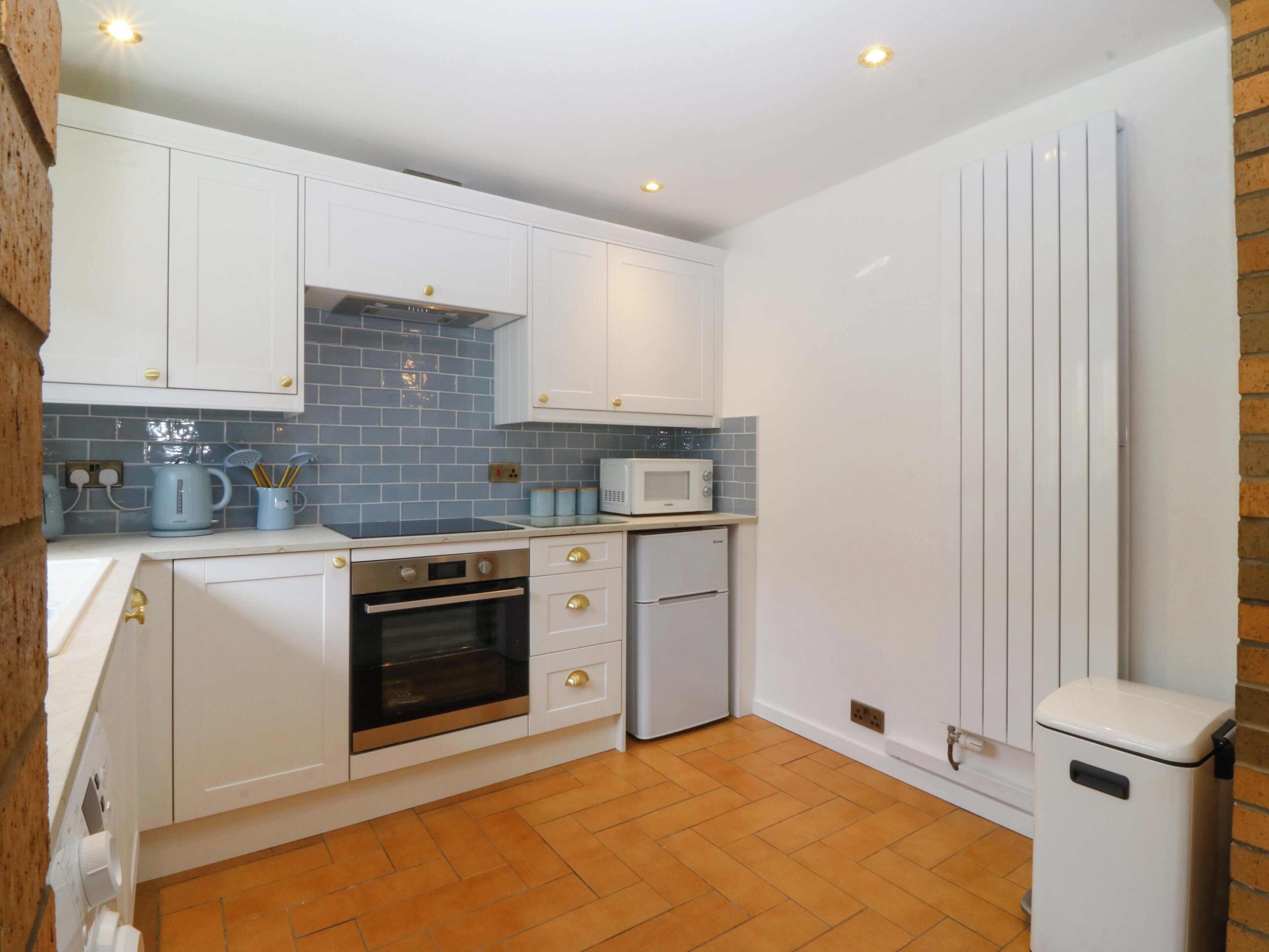 A kitchen with white cabinets, a microwave, an oven, and a refrigerator.