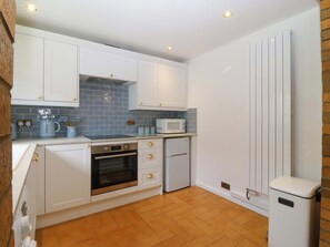 A kitchen with white cabinets, a microwave, an oven, and a refrigerator.