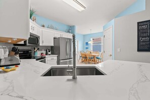 Een moderne keuken met witte kastjes, een roestvrijstalen koelkast en een marmeren aanrecht.