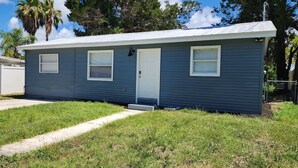 A single-story, blue house with a white door, two windows with shutters, and a small front porch. - 2-bedroom house in fantastic Hudson with cool AC breeze (Hudson)