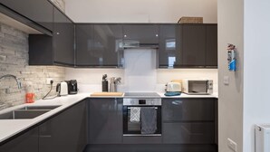 Ett modernt kök med mörka skåp, en inbyggd ugn, en mikrovågsugn och en kaffebryggare.