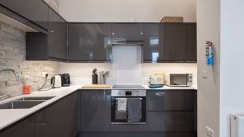 A modern kitchen with dark cabinets, a built-in oven, a microwave, and a coffee maker.
