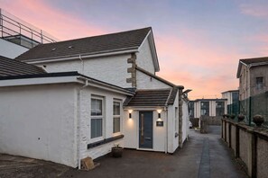A narrow street with white buildings, a visible door, and a small garden area. - The Jailhouse, Historic Flat in Central Newquay (Newquay)