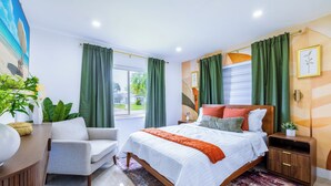Un dormitorio moderno con una cama grande, un escritorio, una silla y un ventanal con cortinas.