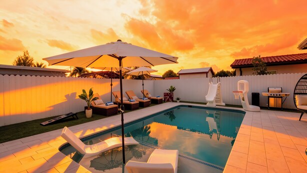 Un patio trasero con piscina, sillas de descanso, un tobogán y una zona de barbacoa.