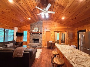 A cabin interior with a stone fireplace, wooden ceiling, a sofa, a bar area, and a refrigerator. - Cloud Nine Cabin Private 2 bed 2 bath 2 Living Hot Tub Outdoor Fireplace Sunroom (Broken Bow)