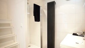 A modern bathroom with a glass shower enclosure, a white sink, and a black radiator. - Holiday Home in Nijkerk With Terrace (Nijkerk)