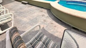 Piscina com espreguiçadeiras e área coberta.