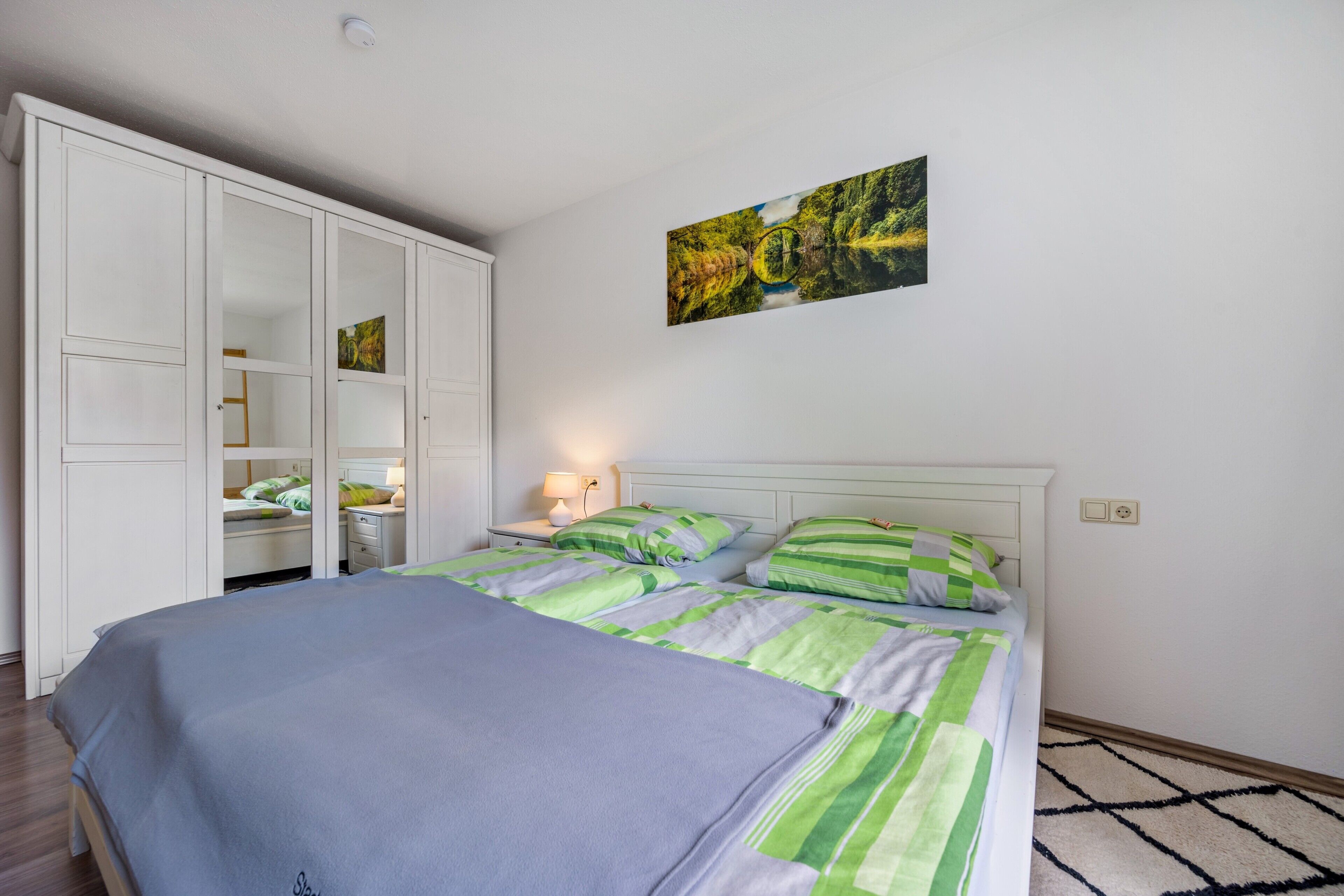 Quarto com cama, guarda-roupa e um quadro na parede.