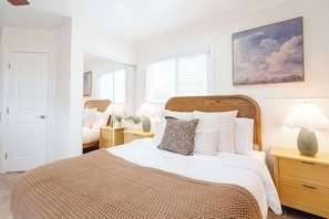 Ein Schlafzimmer mit einem großen Bett, Nachttischen, einem Spiegel und einem Gemälde an der Wand.