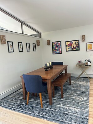 A dining area with a wooden table, blue chairs, a patterned rug, and framed artwork on the walls. - Spacious 3-bedroom house in rural Southeast Boulder, Fairview Estates. (Boulder)