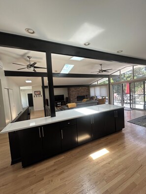 A modern kitchen with a large island, black cabinets, and a stone accent wall. - Spacious 3-bedroom house in rural Southeast Boulder, Fairview Estates. (Boulder)