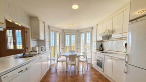 Una cucina moderna con mobili bianchi, un tavolo da pranzo con sedie, un forno integrato e un'ampia finestra.