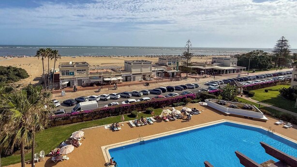 Un hotel con piscina, vista sulla spiaggia e parcheggio.