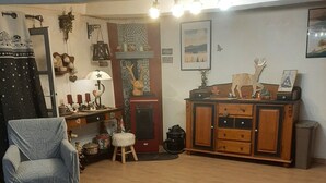 Une pièce comprenant un fauteuil bleu, un meuble en bois, un tapis à motifs et divers objets décoratifs accrochés aux murs.