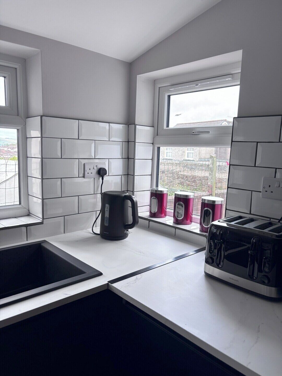 A modern kitchen with a built-in sink, a kettle, and a toaster on the counter.