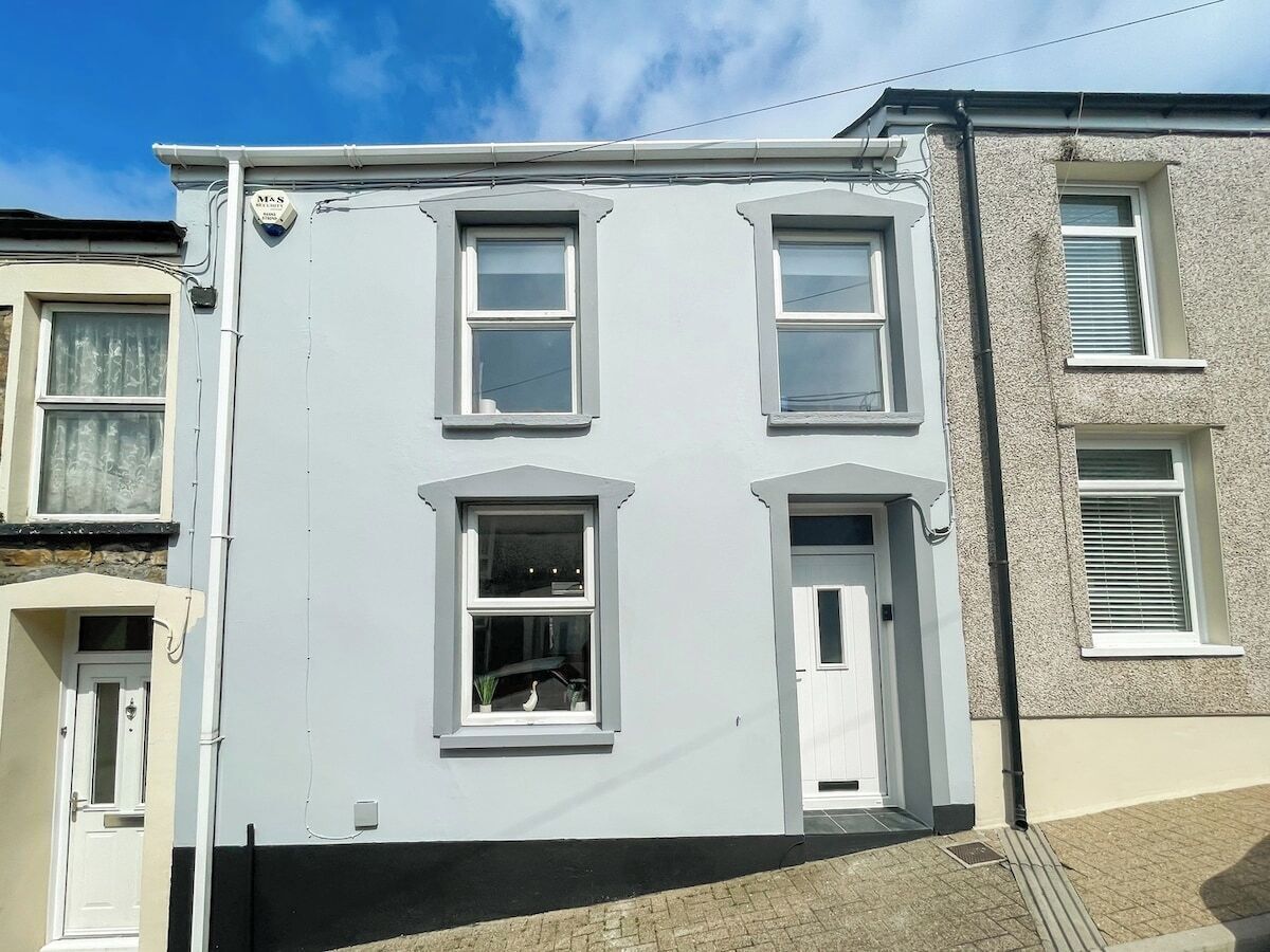 A two-story residential building with a white facade, multiple windows, and a visible door.