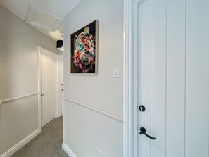 A hallway with a white door, a light switch, and a wall-mounted artwork. - Mulberry House - close to BPW and Brecons (Dowlais)