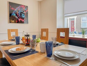 Ein Essbereich mit einem Holztisch, gedeckt für das Frühstück, einschließlich Tellern, Gläsern und einer Obstschale.