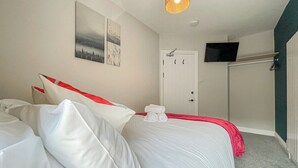 Ett hotellrum med en säng, en platt-TV som är monterad på väggen och en dörr med ett handtag.
