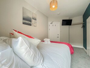 A hotel room with a bed, a flat-screen TV mounted on the wall, and a door with a handle. - Mulberry House - close to BPW and Brecons (Dowlais)