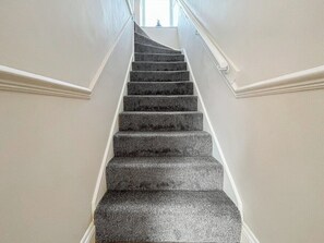 Eine Treppe mit Geländer, Teppichstufen und weißem Wandverkleidung.